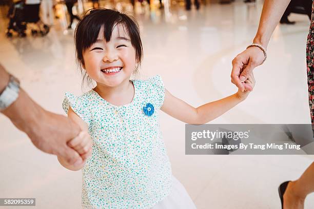 little girl holding hands with mom & dad joyfully - mother daughter holding hands stock pictures, royalty-free photos & images