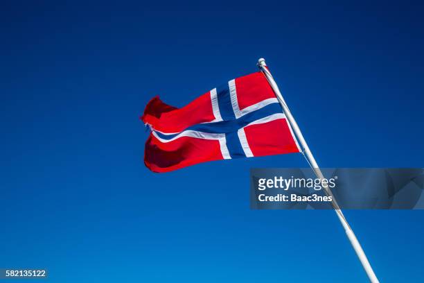 the norwegian flag with blue sky in the background - norway flag stock pictures, royalty-free photos & images
