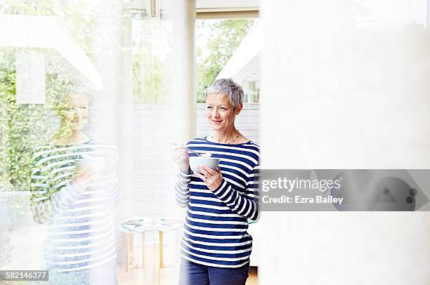 woman looks out of her window eating breakfast - breakfast top view stock pictures, royalty-free photos & images