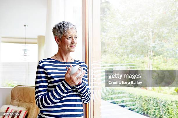 woman smiling looking out of window with coffee - striped shirt stock pictures, royalty-free photos & images