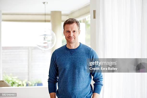 honest portrait of a man in apartment - long sleeved stock-fotos und bilder