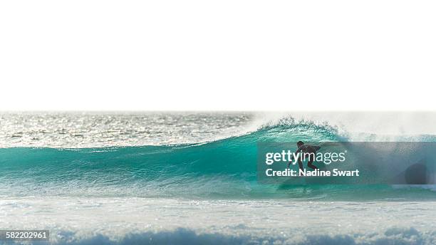 surfer silhouette on blue wave - surf fotografías e imágenes de stock
