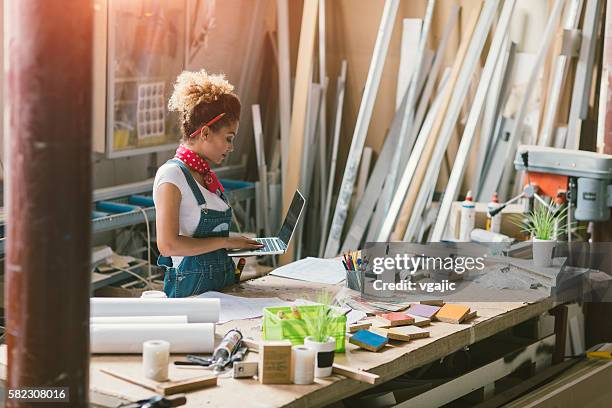 latina carpenter standing in her workshop - leanincollection stockfoto's en -beelden