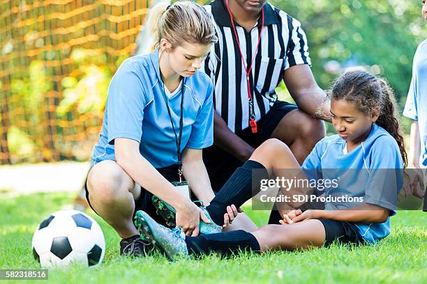 verletzte fußballerin bekommt ihren knöchel von ihrem trainer überprüft - sports injury stock-fotos und bilder