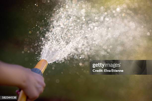 close up of child using garden water hose - wet hose ストックフォトと画像