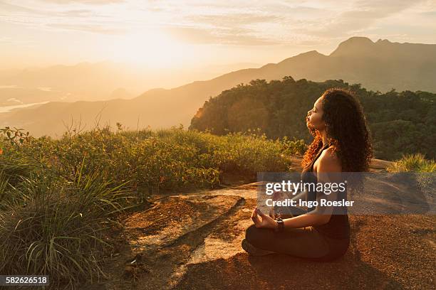 young woman meditating on mountain top - yoga outdoor stock pictures, royalty-free photos & images