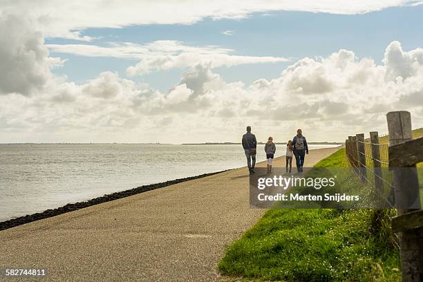 family hiking along dyke and sea - friesland netherlands stock pictures, royalty-free photos & images