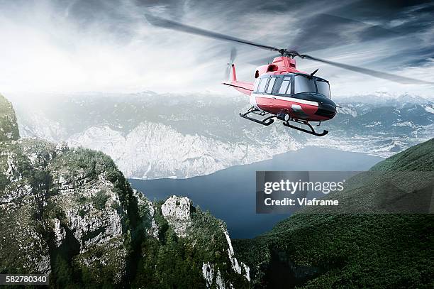 helicopter flying over mountains and a lake - rescate fotografías e imágenes de stock