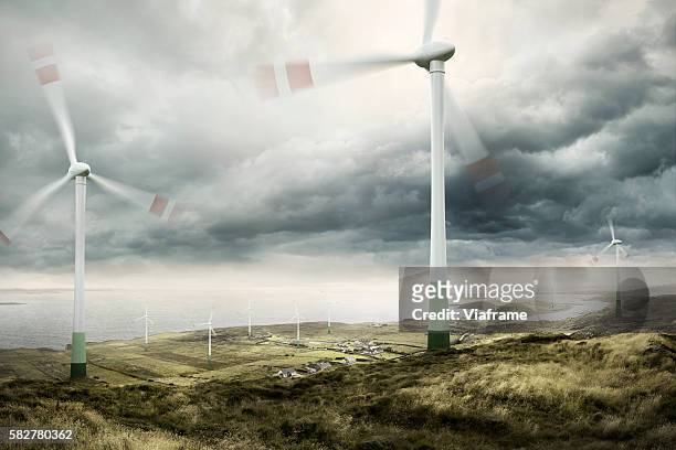 wind turbines with moving rotors and cloudy sky - wind turbines stock-fotos und bilder