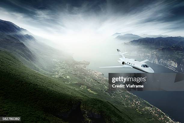 private jet flying above lake - avión privado fotografías e imágenes de stock