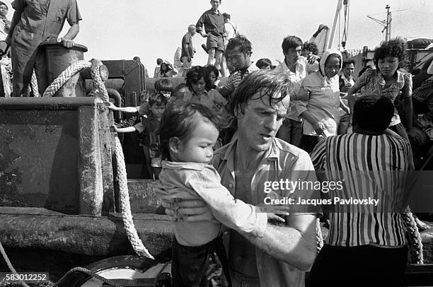 French Doctor Bernard Kouchner carries a Vietnamese refugee child on to the French hospital boat l'Ile de Lumiere, commissioned by Medecins sans...