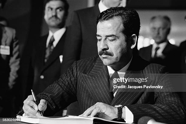 Saddam Hussein signing the visitor's book.