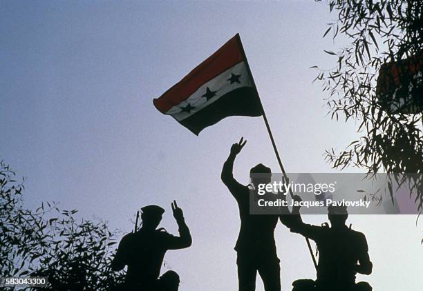 Silhouette of Iraqi soldiers raising their flag and making victory signs after an offensive that led them inside the Iranian border in 1980. War...