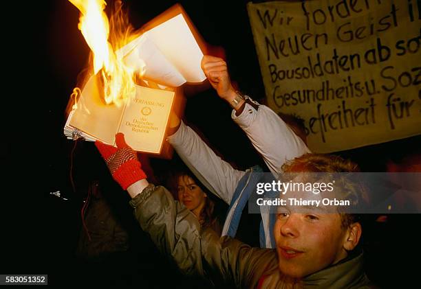 Demonstrators in Leipzig, East Germany, burn the country's constitution during an evening rally. Days earlier, on November 9th, the border separating...