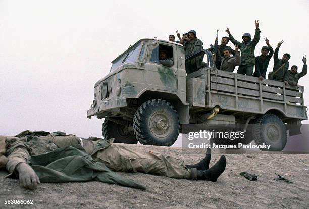 Iraqi soldiers on the southern front rejoice as they pass in front of the body of a dead Iranian soldier after fighting took place around Basra in...