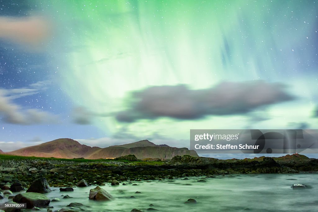Green northern lights over the rocky coast Norway