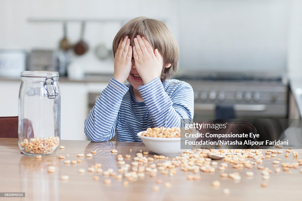 Boy eating bowl of cereal in kitchen