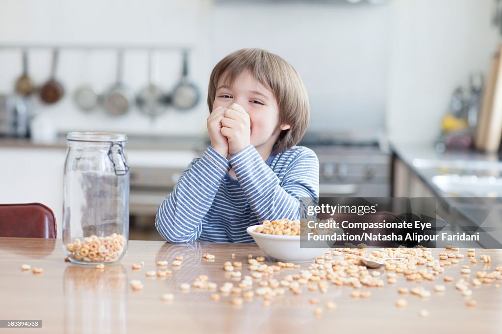 Boy eating bowl of cereal in kitchen