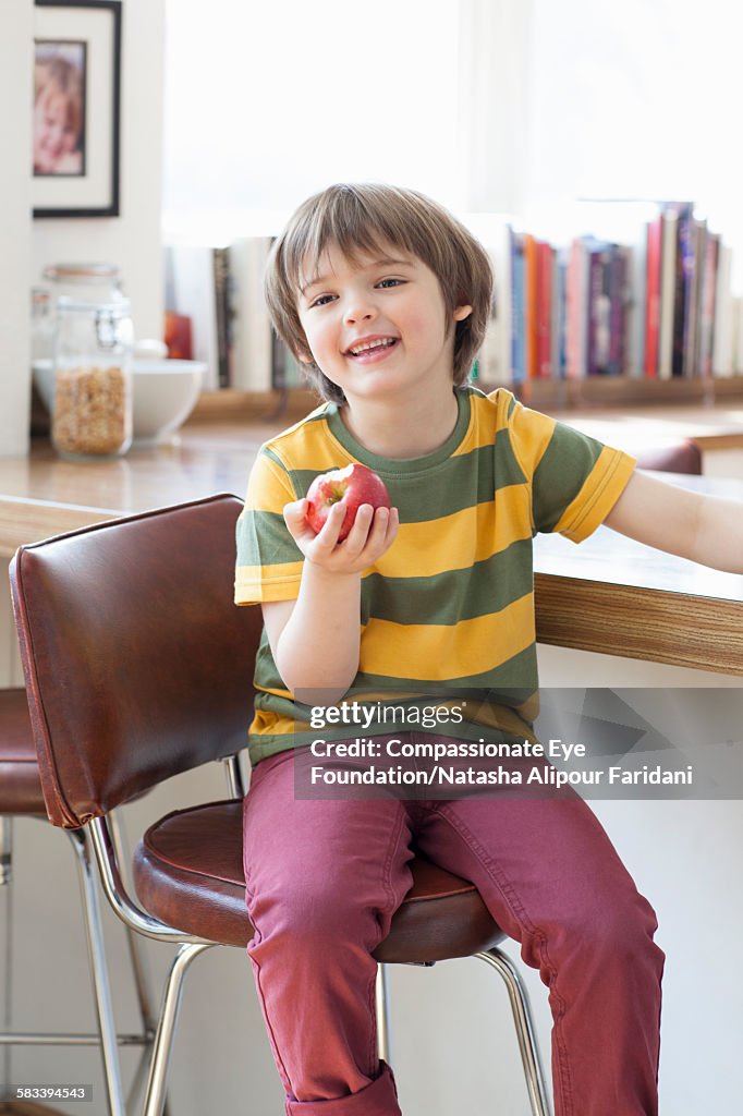 Boy eating apple in kitchen