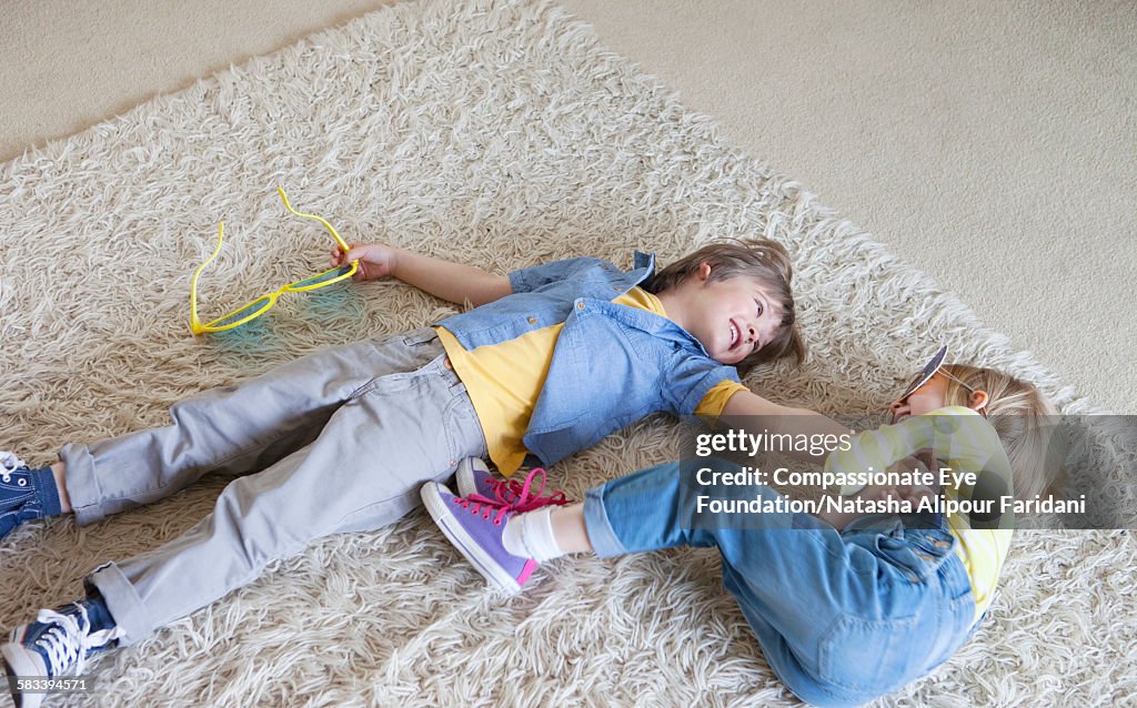 Boy and girl messing about on rug in living room