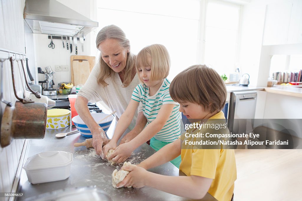 Grandmother decorating cookies with grandchildren