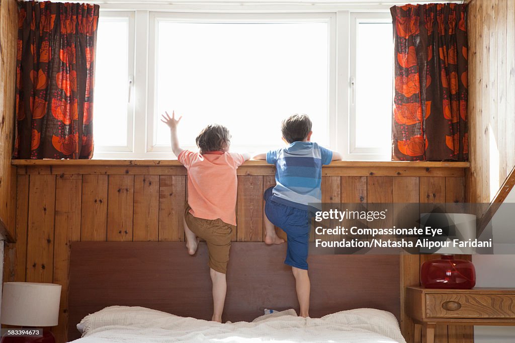 Siblings looking out of bedroom window