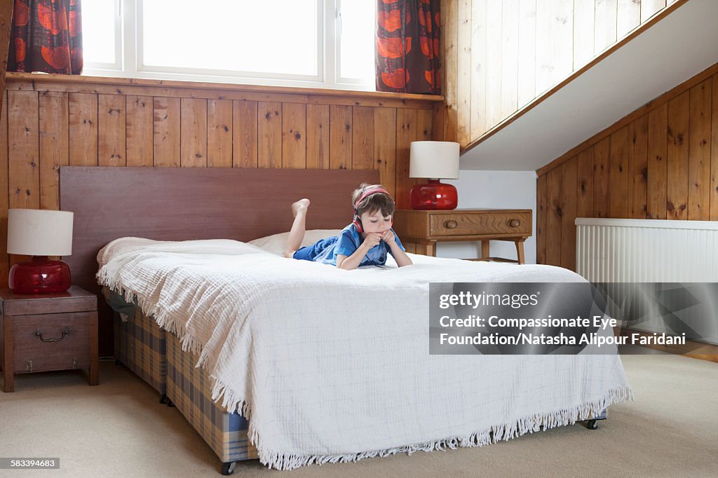 Boy on bed listening to music with headphones