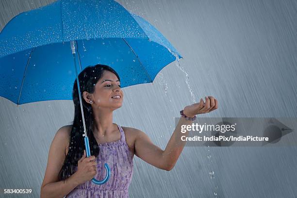 woman with umbrella enjoying the rain - india monsoon stock-fotos und bilder