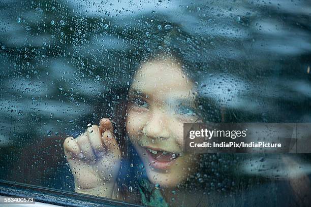 little girl looking out of car window - car rain stock pictures, royalty-free photos & images