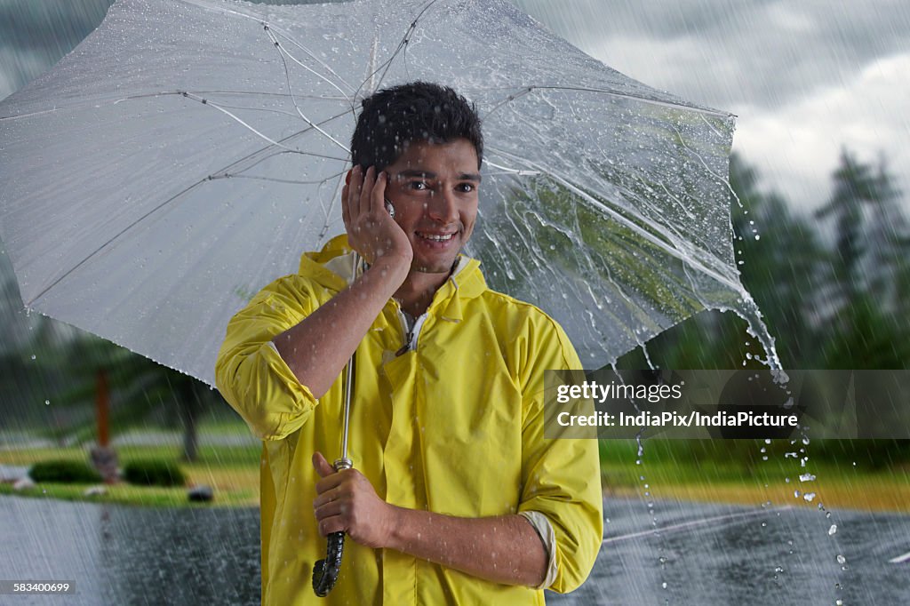 Man with umbrella talking on mobile phone