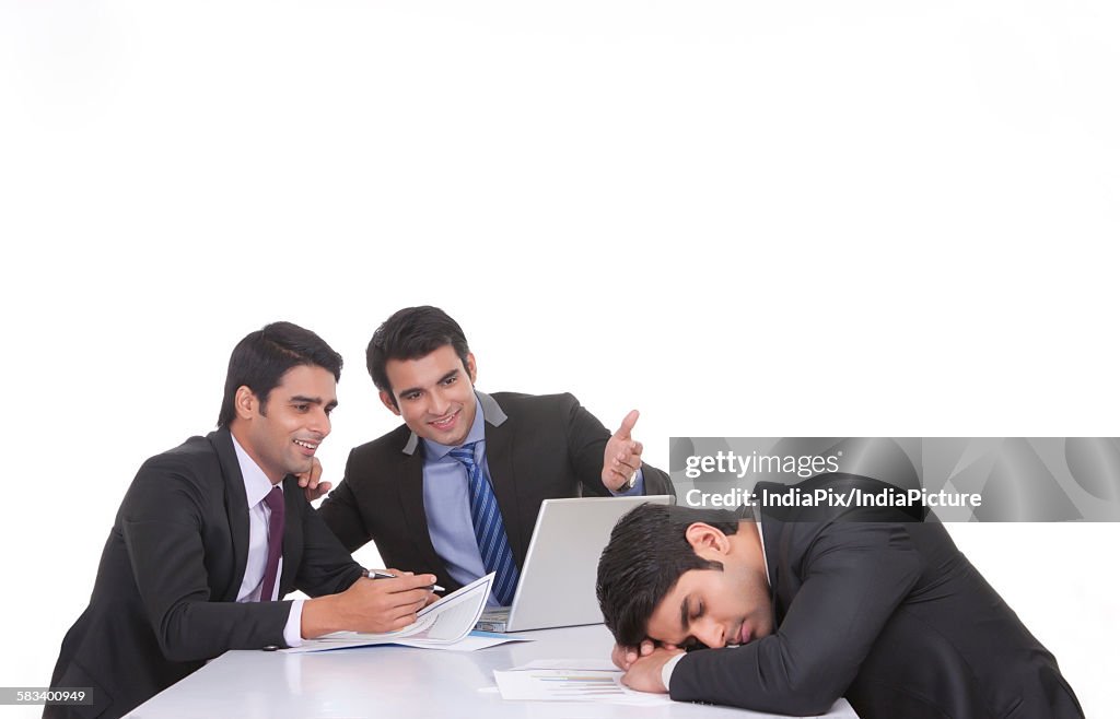 Colleagues making fun of fellow businessman sleeping