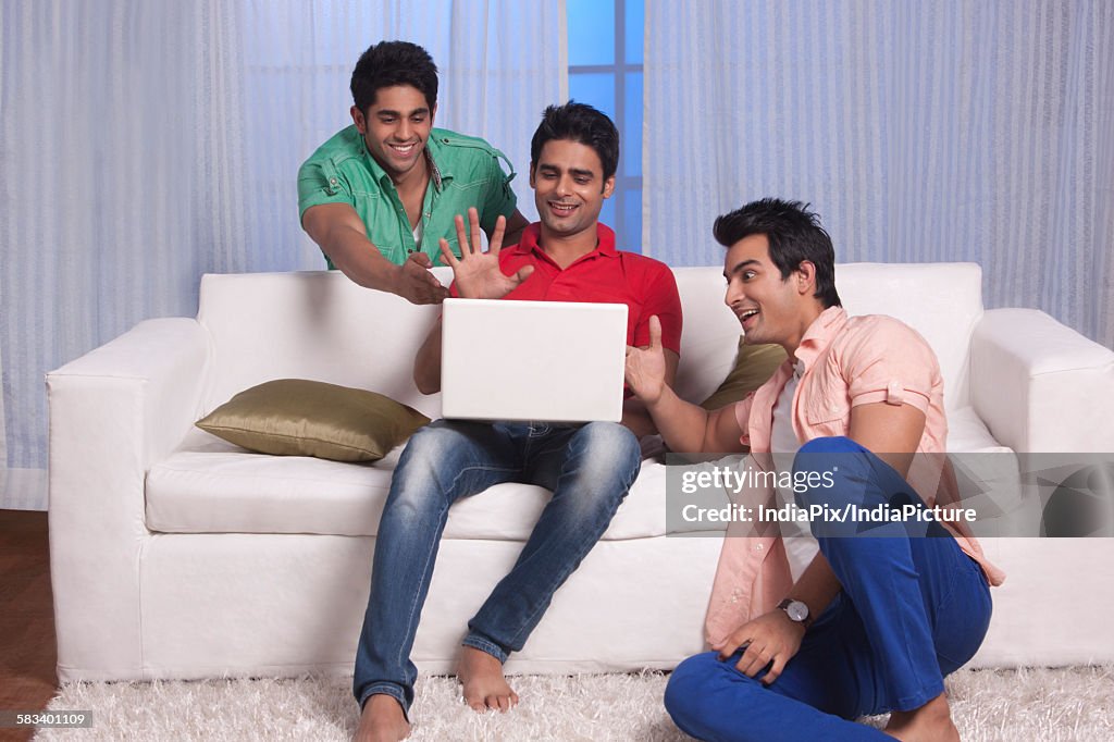 Men gesturing at their friends laptop