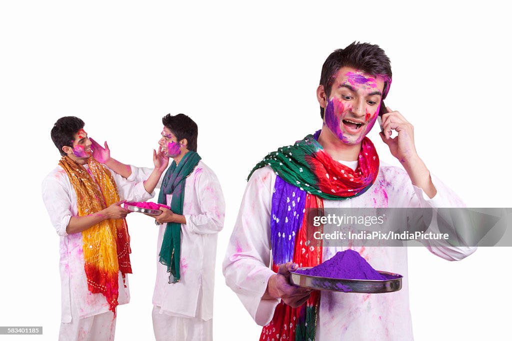 Young man with holi colour talking on a mobile phone