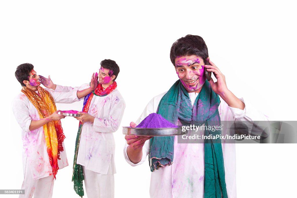 Young man with holi colour talking on a mobile phone