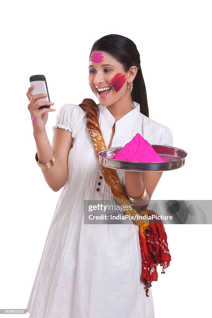 WOMEN with holi colour reading an sms on mobile phone