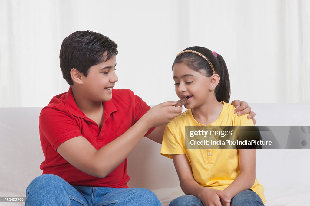 Brother feeding sister chocolate