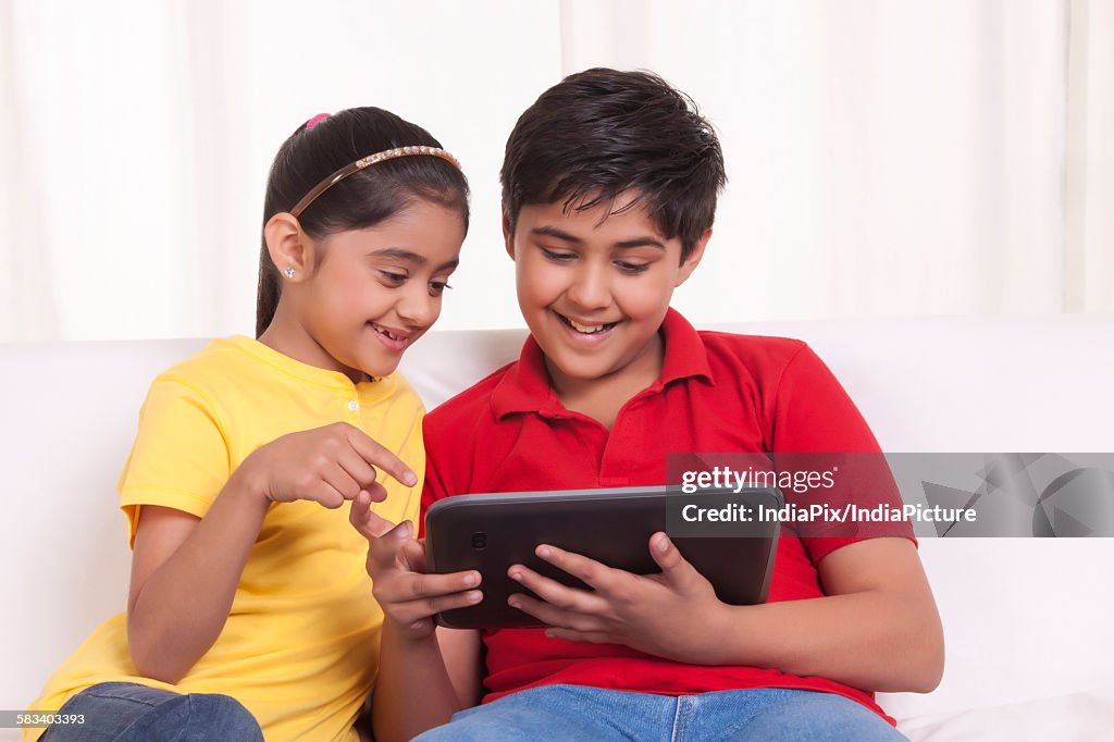 Brother and sister using digital tablet