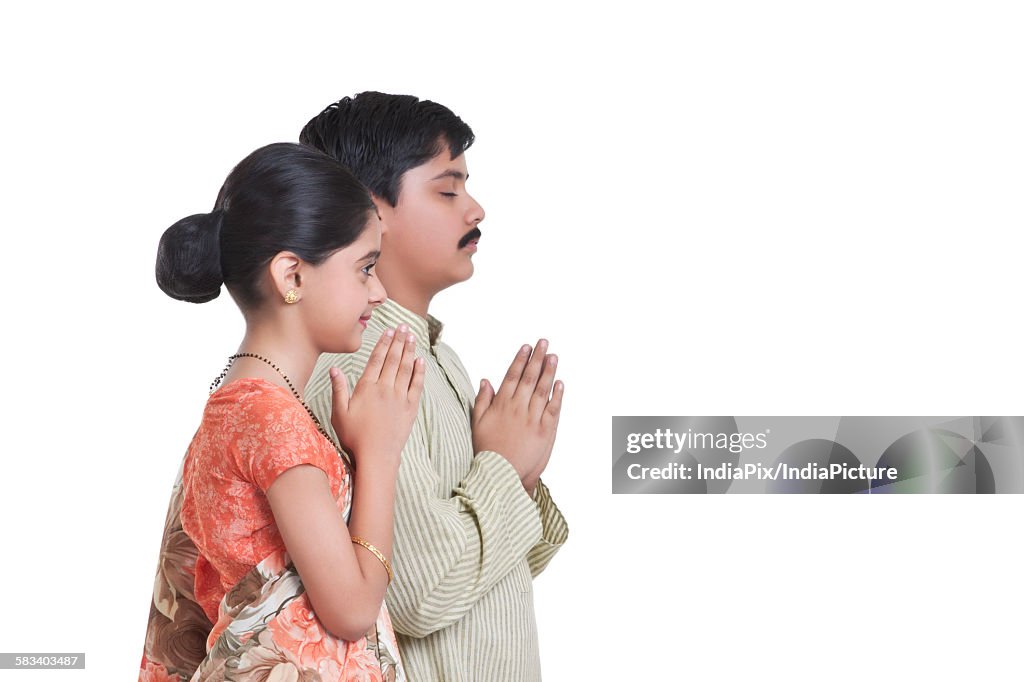 Side profile of kids dressed as husband and wife praying