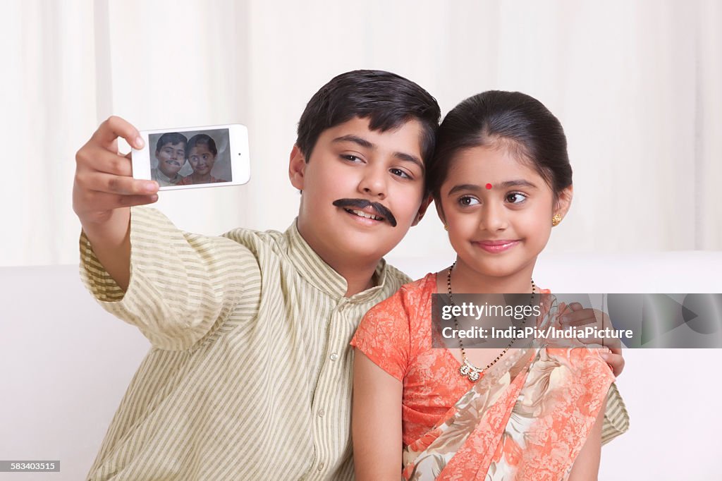 Kids dressed as husband and wife taking a self portrait