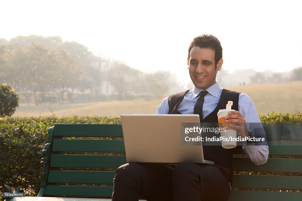 Businessman with a laptop and drink , INDIA , DELHI
