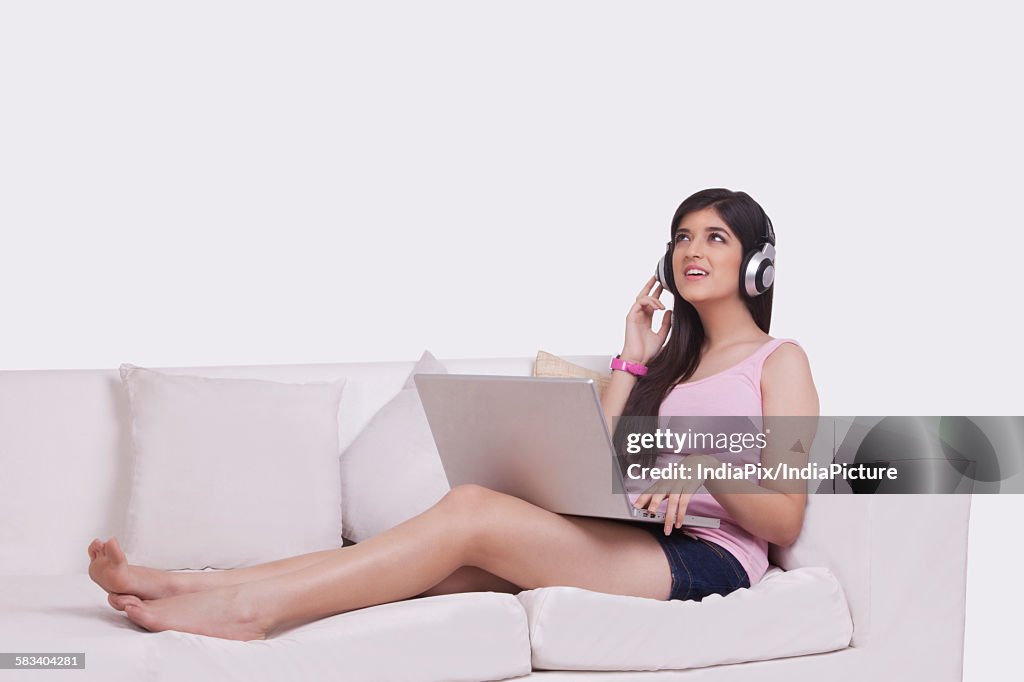 Young woman working on a laptop with headphones on