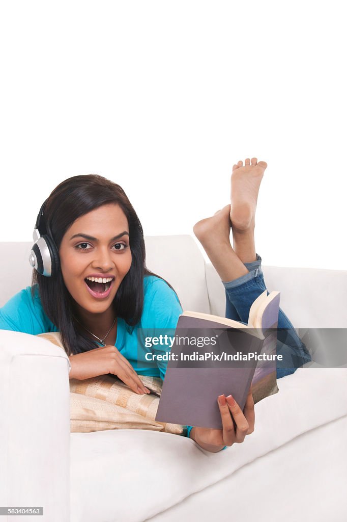 Young woman listening to music while reading