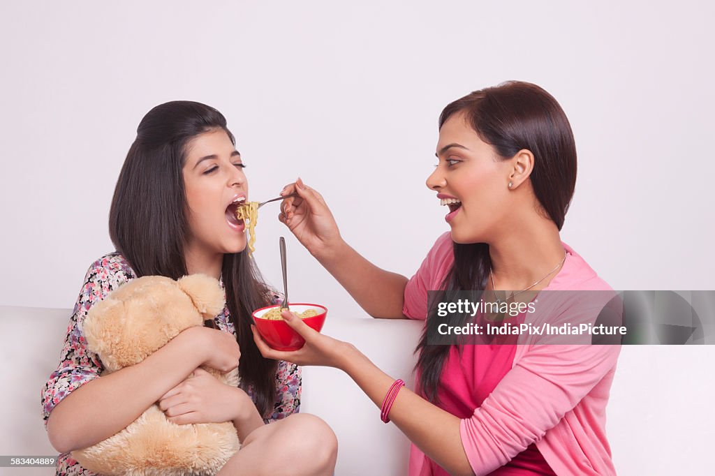 Two young women eating noodles