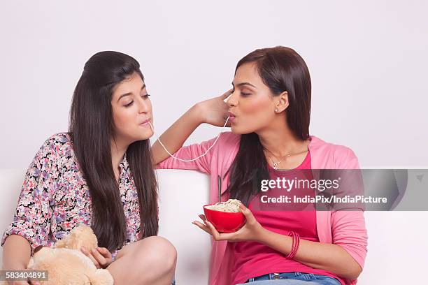 two young women eating noodles - maggi noodles stock pictures, royalty-free photos & images