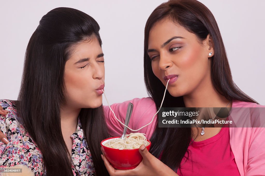 Two young women eating noodles