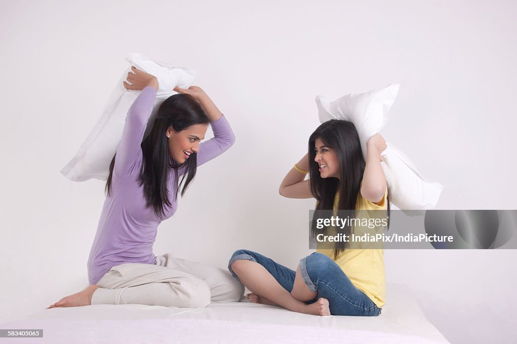Two sisters having a pillow fight