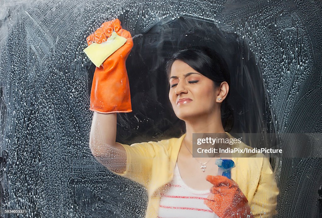 Young woman cleaning a window