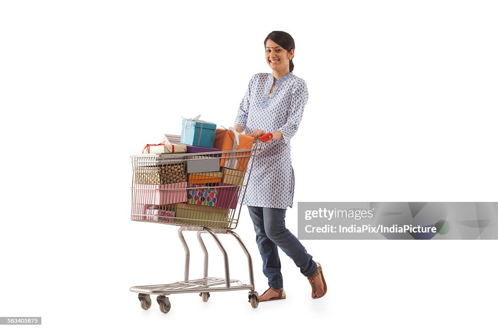 Young woman holding a cart full of gifts