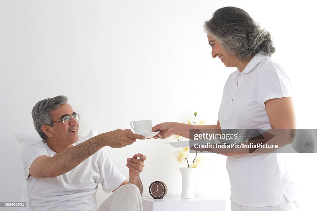 Wife serving tea to her husband