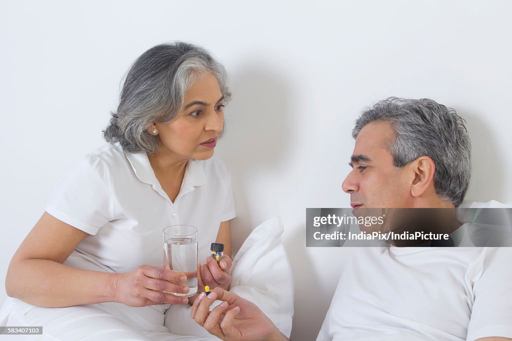 Wife giving medication to husband